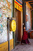 Ein junger Mönch, in leuchtenden Farben gekleidet, in einem bhutanischen Kloster. Bhutan, Asien