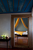 Blick in einen Raum mit einem Bett, hellgelber Stoff, Palacio Belmont, in Lissabon, Portugal.