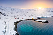 Schneebedeckte Straße in Richtung des Fischerdorfes von Breivikbotn bei Sonnenuntergang, Soroya-Insel, Hasvik, Troms og Finnmark, Nordnorwegen, Skandinavien, Europa