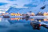 Beleuchtetes Dorf von Sorvaer gespiegelt im kalten Meer während der Winterdämmerung, Soroya-Insel, Troms og Finnmark, Nordnorwegen, Skandinavien, Europa