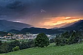 Brunico / Bruneck, Provinz Bozen, Südtirol, Italien. Gewitter und Sonnenuntergang über der Stadt Bruneck