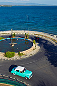 View from above on a classic car driving on a roundabout near the sea in Cienfuegos, Cuba