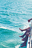 View on peoples legs dangling on a boat at sea in Varadero, Cuba