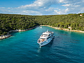 Luftaufnahme von Kreuzfahrtschiff in unberührter Bucht bei einem Halt zum Schwimmen für Passagiere, nahe Kampor, Primorje-Gorski Kotar, Kroatien, Europa