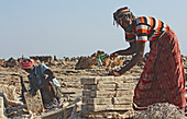 Ethiopia; Afar region; Danakil Desert; Danakil Depression; Workers on the salt pans; loosening and processing the salt plates in laborious manual work; mostly in oppressive heat; Salt plates are tied into packages for transport