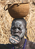 Ethiopia; Southern Nations Region; southern Ethiopian highlands; Mago National Park; lower Omo River; young Mursi woman with traditional lip dish and face-painting; Terracotta lip plate with painted and incised patterns