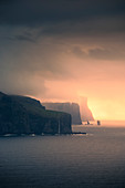 Sonnenuntergang mit Wolken an der Küste von Eysturoy mit steilen Klippen und Felsformation Risin og Kellingin, Färöer Inseln