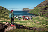 Frau beim Wandern mit Blick auf Dorf Tjørnuvík auf Streymoy auf Färöer Inseln bei Tag\n