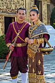 Happy wedding couple in gorgeous Laotian wedding attire during photo shoot at Wat Xieng Thong Temple, Luang Prabang, Luang Prabang Province, Laos, Asia