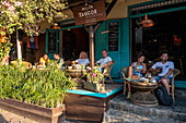 Menschen sitzen vor Restaurant und Bar in der Sisavangvong Road (der Hauptstraße), Luang Prabang, Provinz Luang Prabang, Laos, Asien