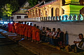 Barefoot monks collect early morning food and drink alms (sai bat), Luang Prabang, Luang Prabang Province, Laos, Asia