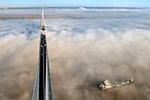 France, between Calvados and Seine Maritime, cargo passing under the Pont de Normandie (Normandy Bridge) that emerges from the morning mist of autumn and spans the Seine, the Natural Reserve of the Seine estuary in the background, view from the top of the south pylon
