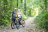 Mature couple checking direction on smart watch in forest