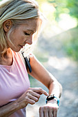 Mature woman operating smart watch in forest