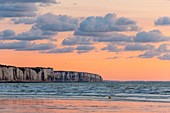 France, Somme, Ault, Sunset on the beach of Ault with an orange sky on the limestone cliffs and reflections on the beach