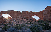 Sunburst and hiker in Windows Arches, Arches National Park, Utah, United States of America, North America
