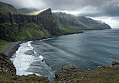 View over a hidden bay with the sun filtering through the clouds, Faroe Islands, Denmark, Europe