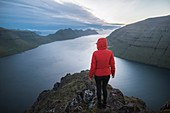 Dänemark, Färöer, Klaksvik, Frau, die auf dem Berg Klakkur über dem Meer steht und die Aussicht betrachtet