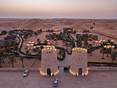 Luftaufnahme vom Eingang zum Arabian Nights Village Wüstenresort inmitten von Dünen bei Sonnenuntergang, Arabian Nights Village, Razeen Area von Al Khatim, Abu Dhabi, Vereinigte Arabische Emirate, Naher Osten