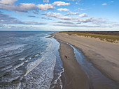 Luftaufnahme von drei Menschen, die auf Pferden am Strand in der Nähe der Westerduinen-Dünen entlang der Nordseeküste reiten, nahe Den Hoorn, Texel, Westfriesische Inseln, Friesland, Niederlande, Europa,