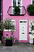 Pink Fassade eines Privathauses mit Fahrrad in Kensington im Frühjahr, London, UK