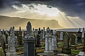 Strahlenbüschel, dramatischer Himmel über Friedhof von Stromness, Orkney, Blick zur Insel Hoy, Schottland UK
