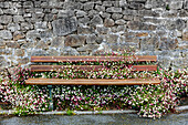 Frankreich, Bretagne, Finistere Sud, alte Steinmauer und Sitzbank mit Blumen bewachsen