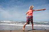 USA, Kalifornien, Ventura, Rückansicht vom Jungen (8-9) läuft am Strand