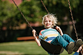 USA, California, San Francisco, Boy (8-9) on swing in park
