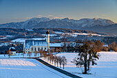 Snow-covered meadows with Wilparting Church and mountains of the Spitzing area in the background, Irschenberg, Upper Bavaria, Bavaria, Germany