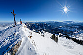 Frau beim Wandern steht am verschneiten Hochgern, Chiemgauer Alpen im Hintergrund, Hochgern, Chiemgauer Alpen, Oberbayern, Bayern, Deutschland