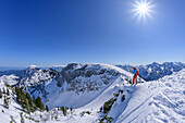 Frau auf Skitour steht am Gratrücken des Rauschberg und blickt in die Tiefe, Rauschberg, Chiemgauer Alpen, Oberbayern, Bayern, Deutschland
