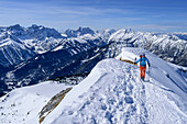 Woman on ski tour climbs up to Schafreiter on foot over ridge of snow, Karwendel, Upper Bavaria, Bavaria, Germany