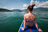 Frau auf SUP Board im Wasser auf dem Iseosee, Italien