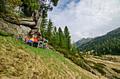 Man and woman while hiking take a break under rocks, Rosanintal, Königstuhl, Nockberge, Nockberge-Trail, UNESCO Biosphere Park Nockberge, Gurktal Alps, Carinthia, Austria