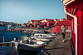 Frau am Hafen im Dorf Kyrkesund auf der Schäreninsel Tjörn an der Westküste von Schweden, blauer Himmel mit Sonne\n