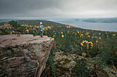 Frau auf der Felsklippe Predikstolen auf dem Getsvedjeberget mit Blick über die Landschaft von Höga Kusten im Osten von Schweden\n