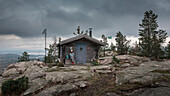 Frau sitzt an Schutzhütte auf dem Gipfel des Valkallen in Höga Kusten im Osten von Schweden\n