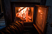 Anfeuern des Saunaofens mit Holz in Lappland, Schweden\n