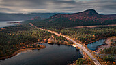 Straße durch Landschaft mit See und Bergen im Stora Sjöfallet Nationalpark im Herbst in Lappland in Schweden von oben\n