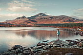 Woman in landscape with mountains and lake in Stora Sjöfallet National Park in autumn in Lapland in Sweden