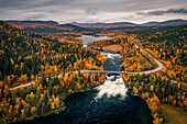 Panoramastrasse Wilderness Road mit Brücke über Stromschnelle und Fluss und Bäumen im Herbst in Jämtland in Schweden von oben\n