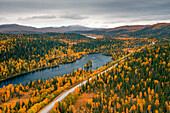 Panoramastrasse Wilderness Road entlang eines Flusses, mit Bergen und Bäumen im Herbst in Jämtland in Schweden von oben\n