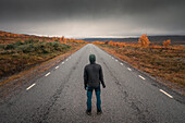 Person auf der Straße der der Wilderness Road, auf der Hochebene Vildmarksvägen in Jämtland im Herbst in Schweden\n