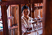 Portrait einer Frau, die an einem Webstuhl aus Holz arbeitet, Myanmar, Asien