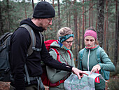 Wandergruppe liest Wanderkarte beim Wandern im Wald im Tiveden Nationalpark in Schweden\n