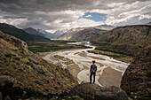 Wanderer blickt von Fels auf das Tal des Vueltas Fluss, El Chalten, Fitz Roy Massiv, Provinz Santa Cruz, Patagonien, Argentinien, Südamerika