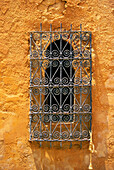 Reich verzierte Schmiedearbeiten am Rundbogenfenster an der Stuckwand, Marrakesch, Marokko