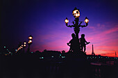 Nachts beleuchtete Laternen mit Turm im Hintergrund, Pont Alexandre III, Eiffelturm, Paris, Ile-de-France, Frankreich