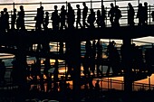 Silhouette of people walking down a ramp at sunset